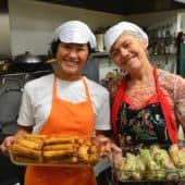 Two women offer hand-made spring rolls.