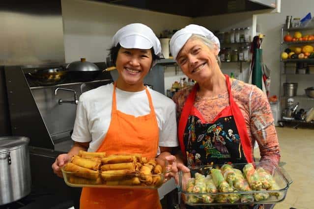 Two women offer hand-made spring rolls.