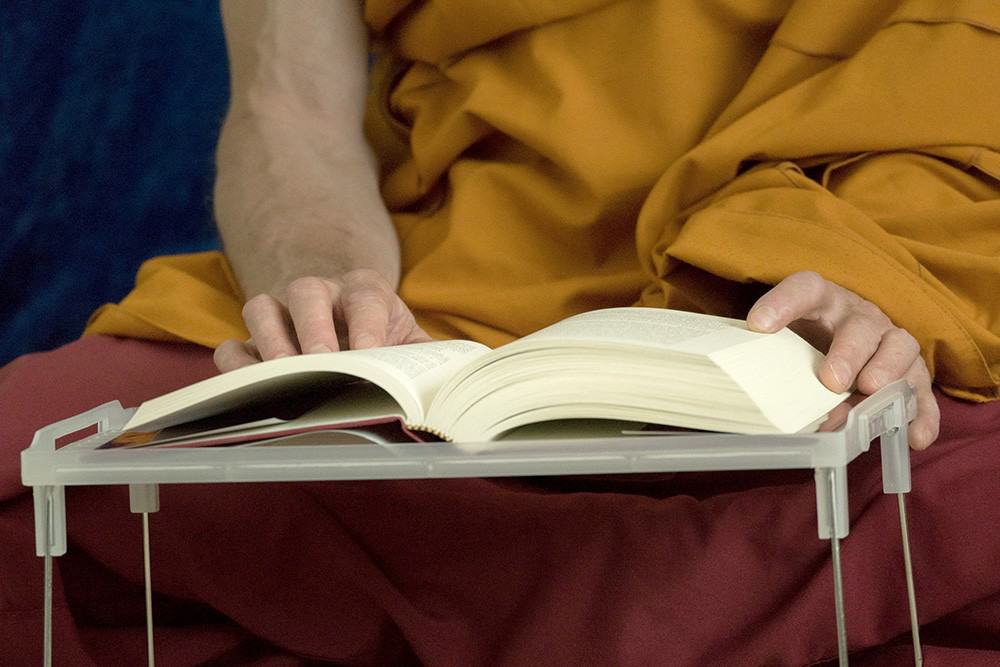 A Tibetan Buddhist monastic reads a book.