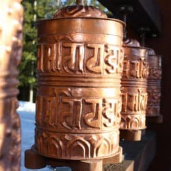 A row of Tibetan prayer wheels in the sunlight.