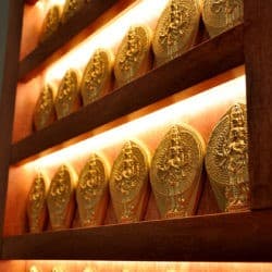 Rows of clay figures of the Buddha of compassion, Chenrezig on illuminated altar shelves.