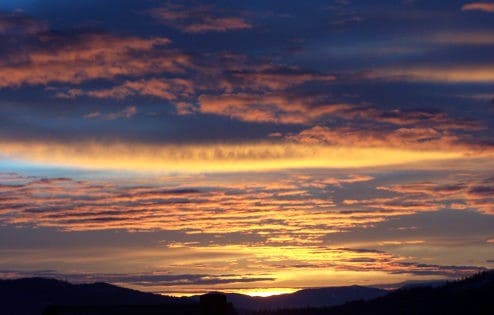 Orange streaks in a cloudy sky as the sun sets.