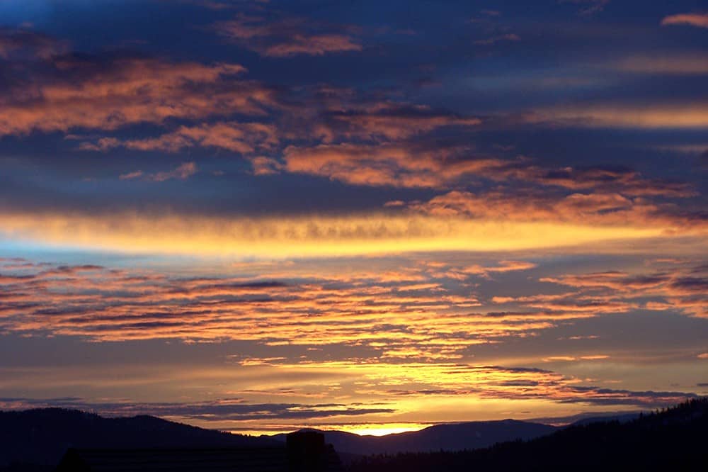 Orange streaks in a cloudy sky as the sun sets.