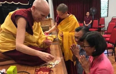 Venerable Chodron gives out mani pills to a couple at Buddhist Gem Fellowship.