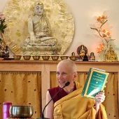 Venerable Thubten Chodron holds up a Dharma book while teaching.