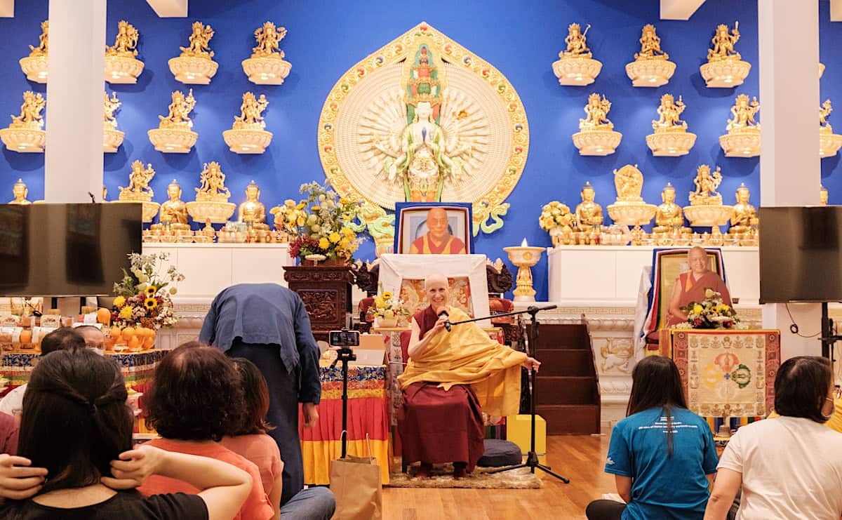 Venerable Chodron teaching in front of a large statue of Chenrezig.