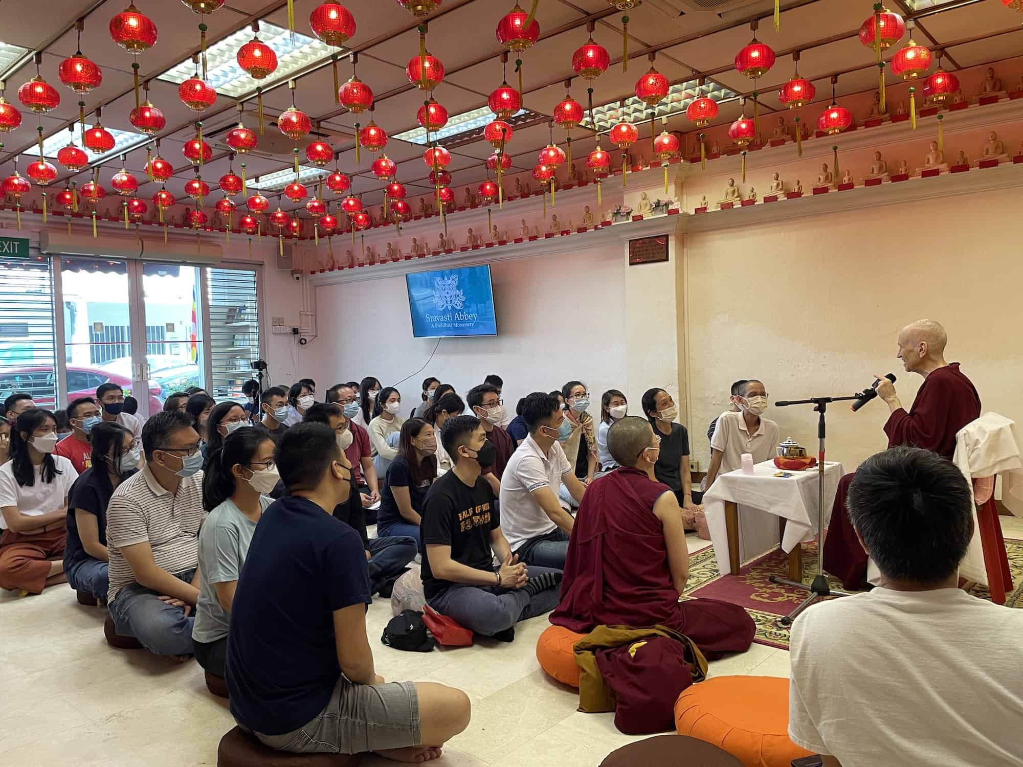 Venerable Chodron teaching in a crowded room of students.