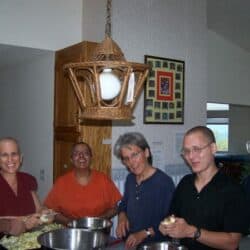 Venerable Chodron and Exploring Monastic Life participants cut apples together.